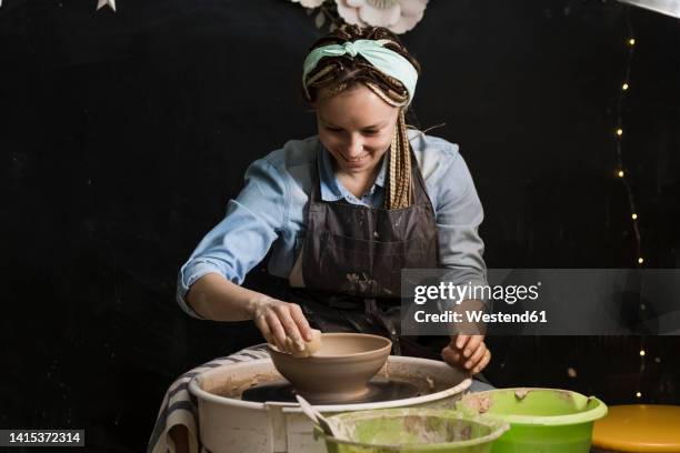 smiling potter moulding shape on pottery wheel at art studio - potters wheel stock pictures, royalty-free photos & images