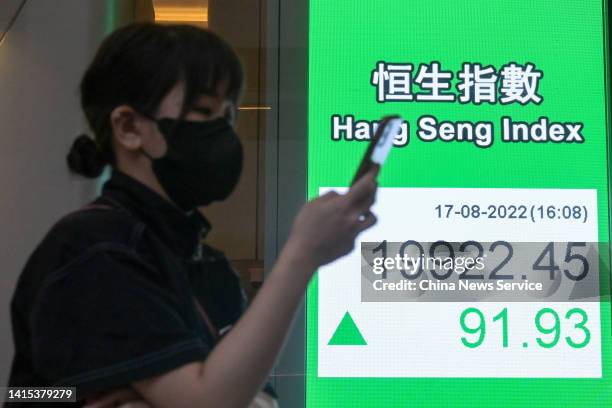 Pedestrian walks by an electronic screen displaying the numbers for the Hang Seng Index on August 17, 2022 in Hong Kong, China.