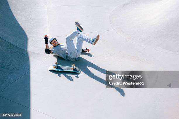 skateboarder falling in skatepark on sunny day - skateboard fall stock-fotos und bilder