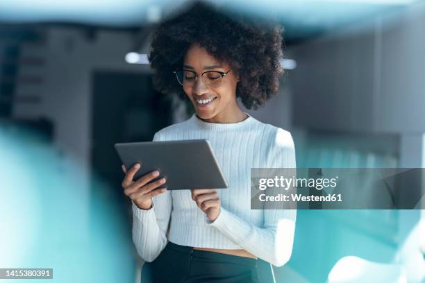 smiling businesswoman using tablet pc at office - differential focus stock pictures, royalty-free photos & images