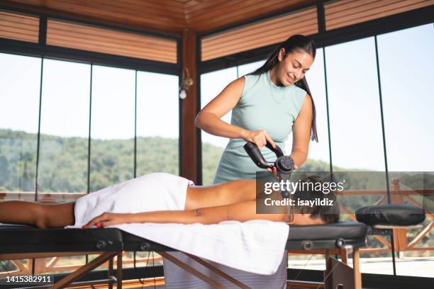 young woman enjoying at spa during back massage in a luxury spa - massager stock pictures, royalty-free photos & images