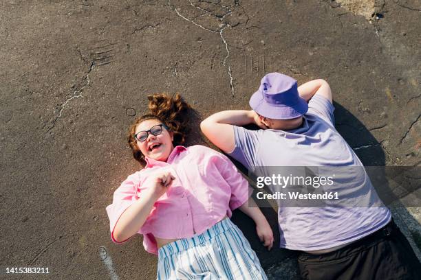 brother and sister with down syndrome lying on footpath on sunny day - plump girls stockfoto's en -beelden