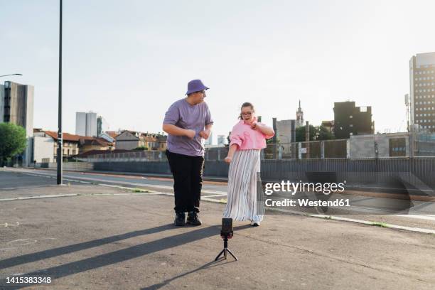 brother and sister dancing and filming video through smart phone on street - teen doing filming imagens e fotografias de stock