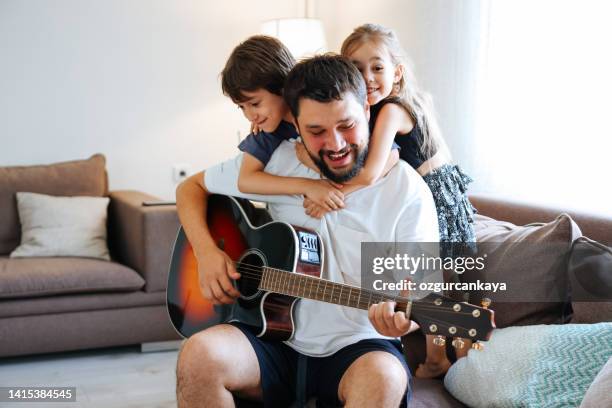 father teaching his son and daughter guitar - plucking an instrument 個照片及圖片檔