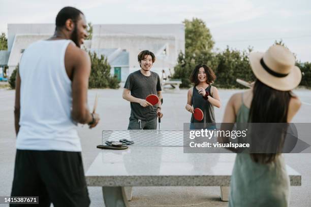 mixed race group of friends playing tabletennis - tafeltennis stockfoto's en -beelden