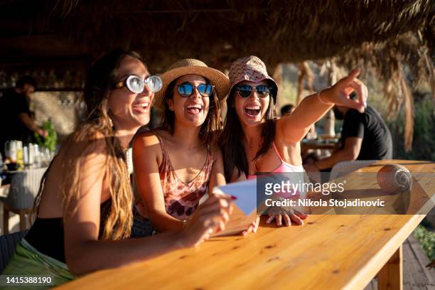 girls having fun cheering with cocktails at bar on the beach - beach cocktail party stock pictures, royalty-free photos & images