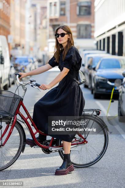 Isis-Maria Niedecken is seen on a bkie wearing black Copenhagen Studios bag, black burgundy Copenhagen Studios boots, black dress August 11, 2022 in...