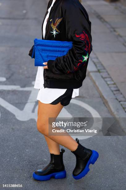 Mathilde Ravn is seen wearing blue Copenhagen Studios bag, black blue Copenhagen Studios boots, black bomber jacket with print, shorts, white button...