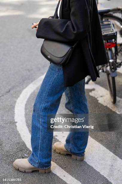 Isis-Maria Niedecken is seen wearing black Copenhagen Studios bag, grey Copenhagen Studios boots, denim jeans, black blazer on August 11, 2022 in...