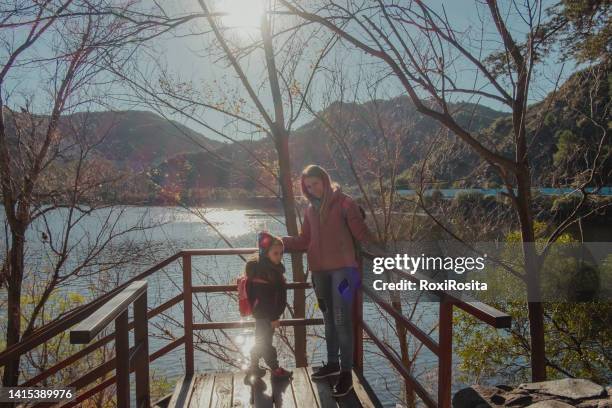 woman and little girl in a viewpoint with a lake and trees on a sunny day. - cordoba argentina fotografías e imágenes de stock