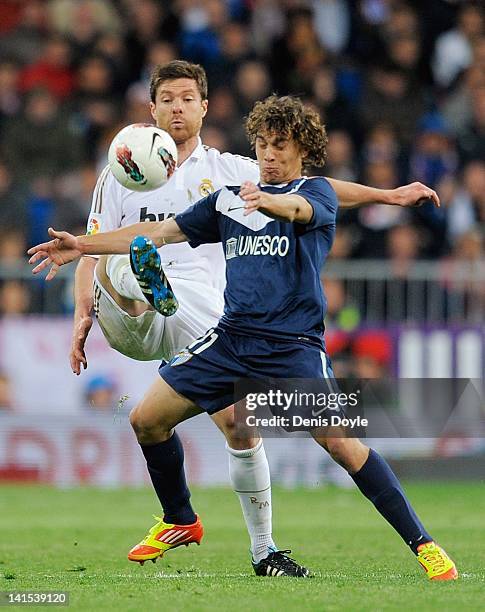 Xabi Alonso of Real Madrid CF competes for the ball against Sebastian Fernandez of Malaga CF during the La Liga match between Real Madrid CF and...