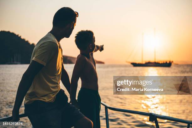 father and son looking out from boat. - father son sailing stock pictures, royalty-free photos & images