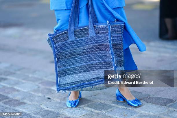 Guest wears a blue oversized long shirt dress, a blue striped print pattern oversized handbag, blue shiny leather slit / split toe-cap ballerinas,...