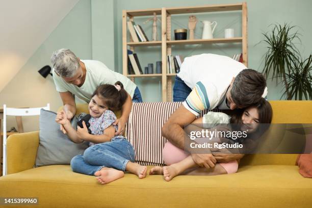 mom and dad tickling their two girls while they're gaming - tickling stock pictures, royalty-free photos & images