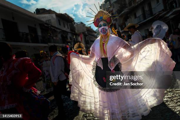 Young Mexican woman, dressed as La Catrina and wearing an embroidered face mask, performs during the Day of the Dead celebrations on October 29, 2021...