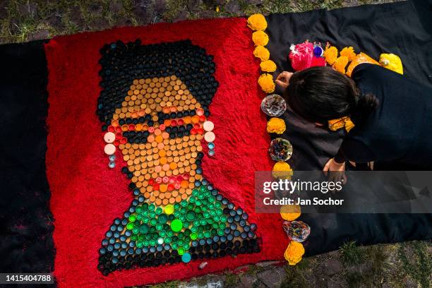 Mexican female artist, employing plastic bottle caps and dyed sawdust, creates a portrait picture of the Mexican painter Frida Kahlo during the Day...