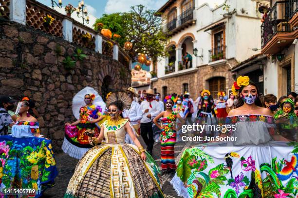 Mexican women, dressed as La Catrina, a Mexican pop culture icon representing the Death, dance in the Day of the Dead parade on October 29, 2021 in...