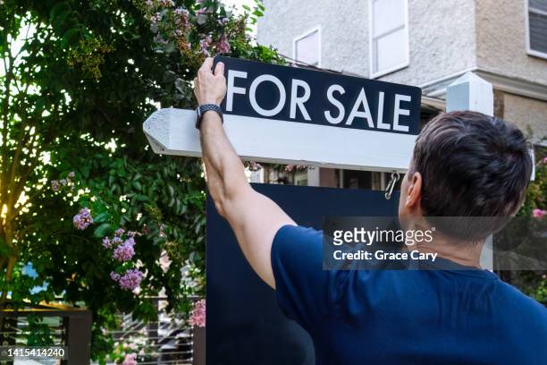real estate agent adjusts for sale sign in front yard - estate agent sign stockfoto's en -beelden