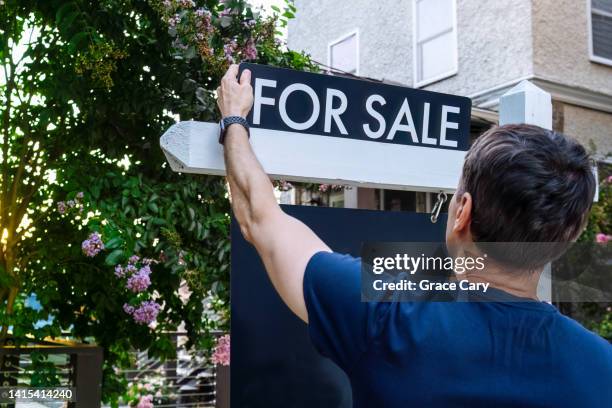 real estate agent adjusts for sale sign in front yard - house sale bildbanksfoton och bilder