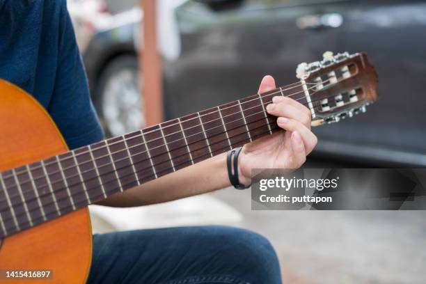 young man playing acoustic guitar at home - fretboard stock pictures, royalty-free photos & images