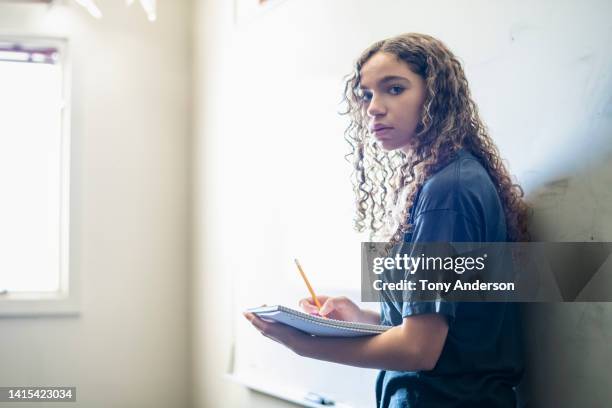 female high school student in classroom writing in notebook - 14 year old biracial girl curly hair stock pictures, royalty-free photos & images