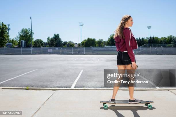 teenage girl skateboarding in high school parking lot - skater girl stock pictures, royalty-free photos & images