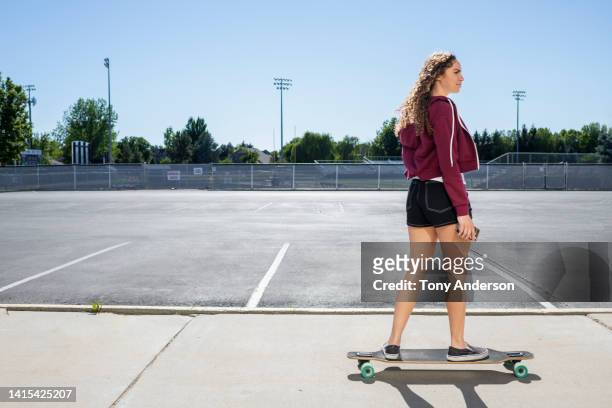 teenage girl skateboarding in high school parking lot - longboard skating 個照片及圖片檔