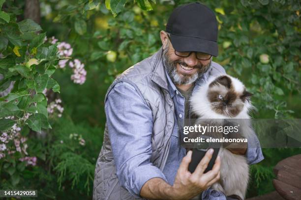 reifer erwachsener mann im garten mit einer katze (selfie, smartphone) - cat selfie stock-fotos und bilder