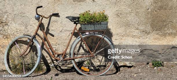a rusty bicycle by a house wall made of plaster - panier de bicyclette photos et images de collection