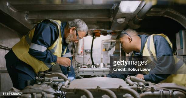 ship mechanics at work, fixing and concentrating on engine an in repair. two men engineers on the job in a large workshop. at the auto service, male colleagues examine a motor in a garage. - repairing boat stock pictures, royalty-free photos & images
