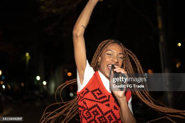 mulher nova cantando com o telefone celular na rua à noite - black culture - fotografias e filmes do acervo