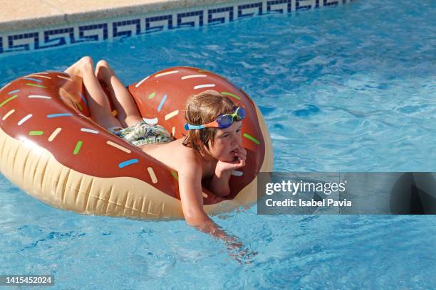 portrait of boy in inflatable ring on swimming pool - rubber ring stock-fotos und bilder