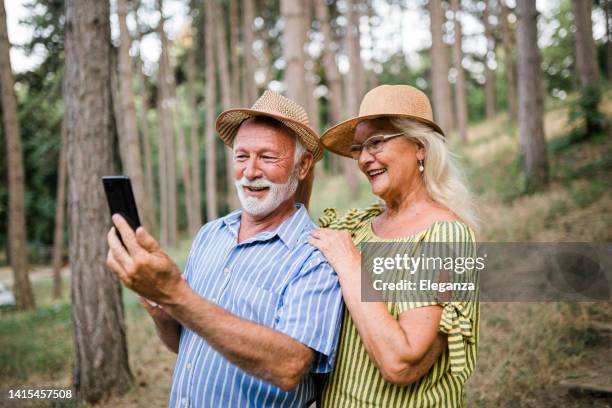 älteres paar mit handy im wald - ageing population stock-fotos und bilder