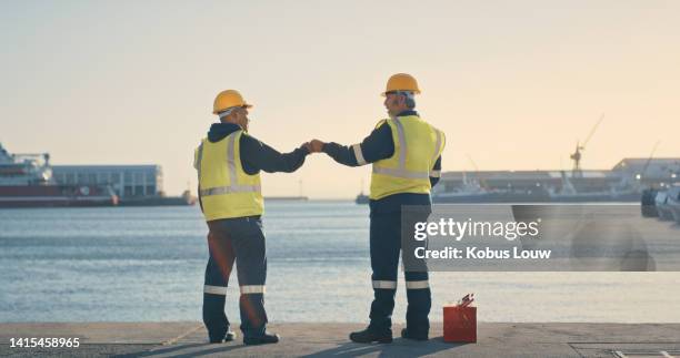 logistics, delivery and shipping engineers looking motivated and ready with fist bump to build vision for ocean or sea cargo dock. excited mechanical technicians with idea for import and export port - water fist stock pictures, royalty-free photos & images