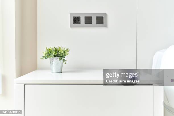small plant in metal pot on bedside table in master bedroom of modern apartment, minimalist decor. - bedside table stock pictures, royalty-free photos & images