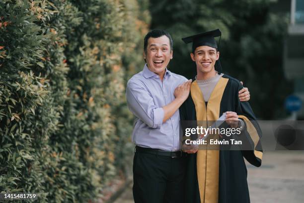 proud asian malay father and son in college graduation gown looking at camera smiling after receiving the certificate diploma - graduation excitement stock pictures, royalty-free photos & images