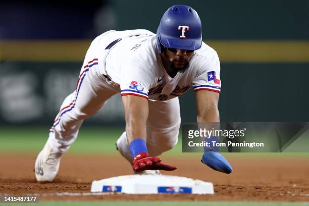 Leody Taveras of the Texas Rangers dives back to first base to beat the throw from Adam Oller of the Oakland Athletics in the bottom of the second...