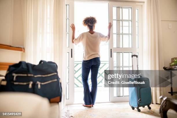 frau mit blick auf den balkon nach der ankunft in ihrem hotel - hotelzimmer tür stock-fotos und bilder