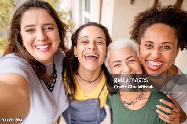 vielfältige gruppe lachender frauen, die gemeinsam selfies draußen machen - gemischte altersgruppe stock-fotos und bilder