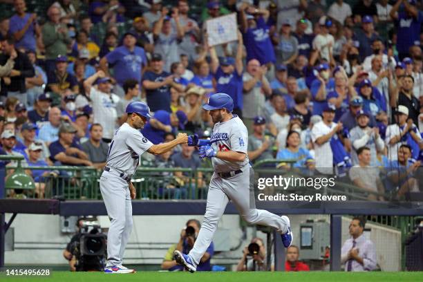 Max Muncy of the Los Angeles Dodgers is congratulated by third base coach Dino Ebel following a home run against the Milwaukee Brewers during the...