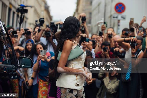 Model Winnie Harlow poses for a crowd of photographers and wears an asymmetrical cream corset Fendi top with a belt and tiny purse accessory, a mint...