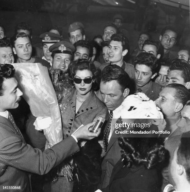 The American actress Ava Gardner and the Italian-American singer and actor Frank Sinatra are surrounded by journalists and onlookers. Milan, May 1953