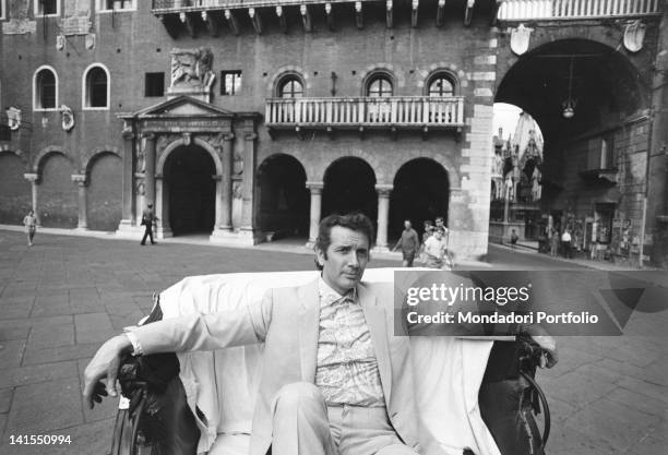 The Italian opera singer Franco Corelli sitting on a armchair in Piazza delle Erbe. Verona, July 1970