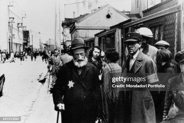 Old Jewish man walking along Ghetto streets with the Star of David on his chest. Warsaw, 1940s