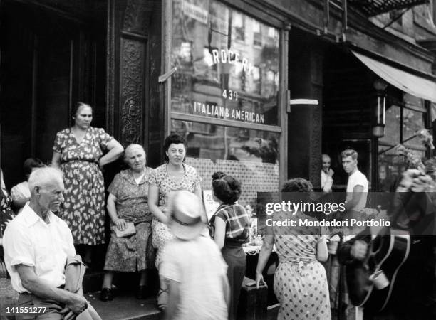 Some Italian American women conversing with each other in front of a grocery store in Little Italy. New York, 1950s
