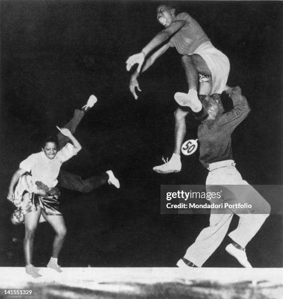 Two Afro-American couples taking part in a competition and dancing the jitterbug, also known as the boogie woogie. USA, 1930s