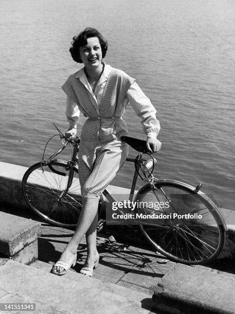 Italian model wearing a 'Brunelli' dress consisting of rayon knee-length trousers with wide braces and a long-sleeve rayon blend shirt. Italy, 1949