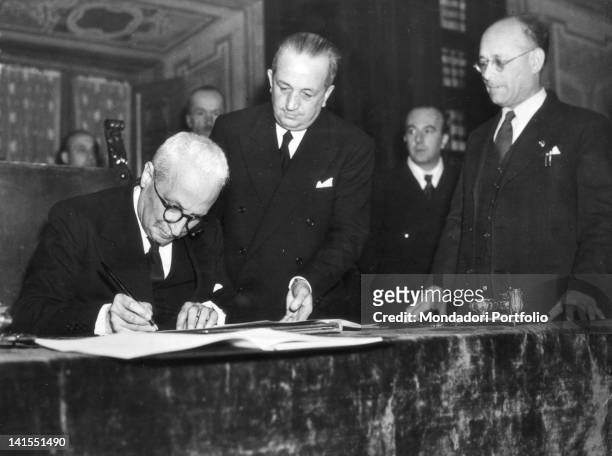 At Palazzo Giustiniani the President of the Italian Republic Enrico De Nicola is signing the Constitution, assisted by the Speaker of the Constituent...