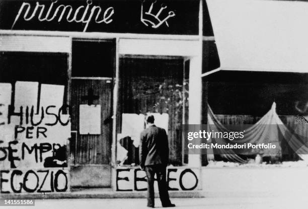 An Italian man watching the anti-Semitic graffiti and broken windows of a Jewish store picked on by Fascists. Trieste, 1942