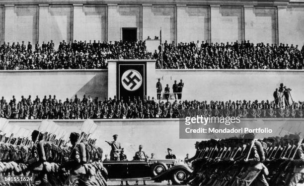 In occasion of the Congress of the Nazi Party, Fuhrer and Chancellor of Germany Adolf Hitler on an open car watching a military parade inside...